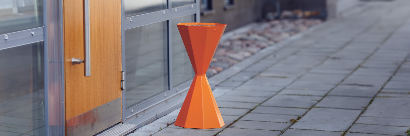 Orange standing ashtray, looks architectural and blends in well with the urban environment.